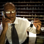 A hotel concierge handing room keys and talking on the phone.